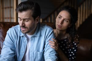 Woman with hand on husbands shoulder looking concerned