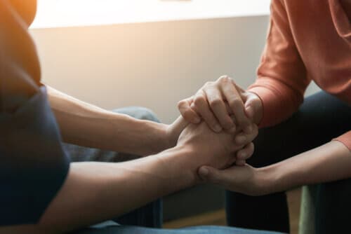 Image of two people holding hands, supporting each other through a difficult time