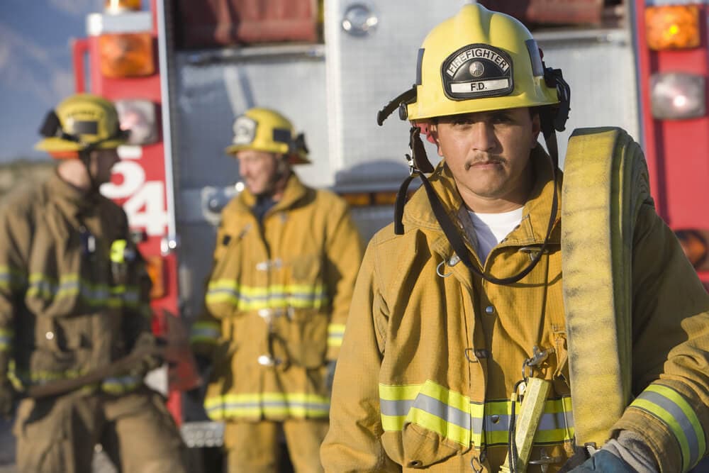 Firefighters in gear holding firehose