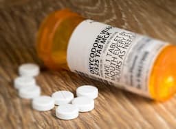Tiltshift effect of prescription bottle for Oxycodone tablets and pills on wooden table for opioid epidemic