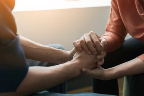 two people holding hands, supporting each other during addiction rehab